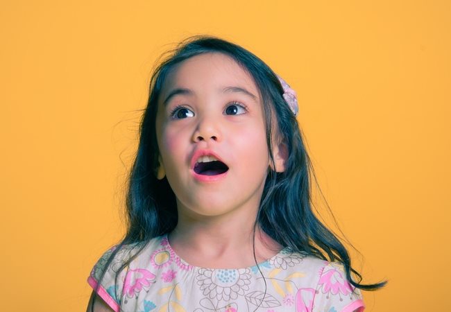 Image of a young girl in awe with a yellow backround