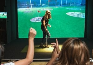 Image of woman playing golf simulator at Topgolf Swing Suite in Freehold NJ